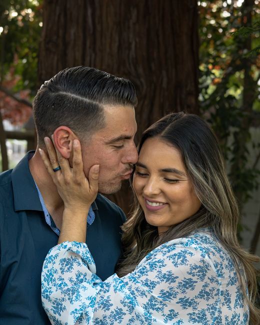 Couple sharing a forehead kiss under a tree