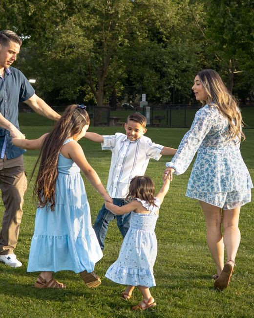 Family holding hands in a circle on the grass