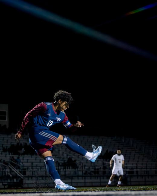 Soccer player mid kick under stadium lights