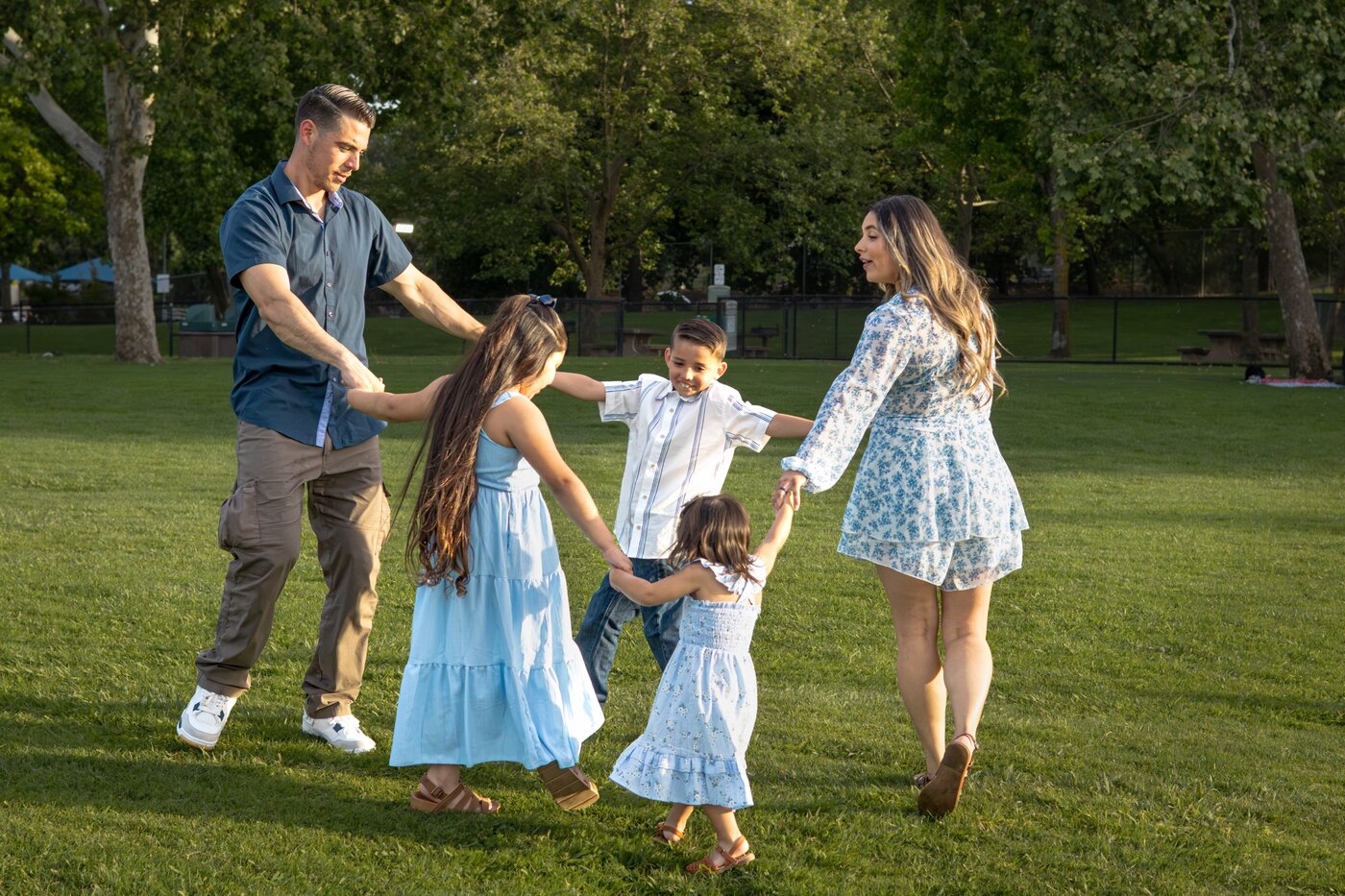 Family playing ring around the rosie in the park